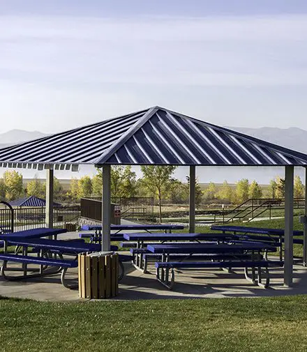 A large blue picnic shelter with benches in the middle.